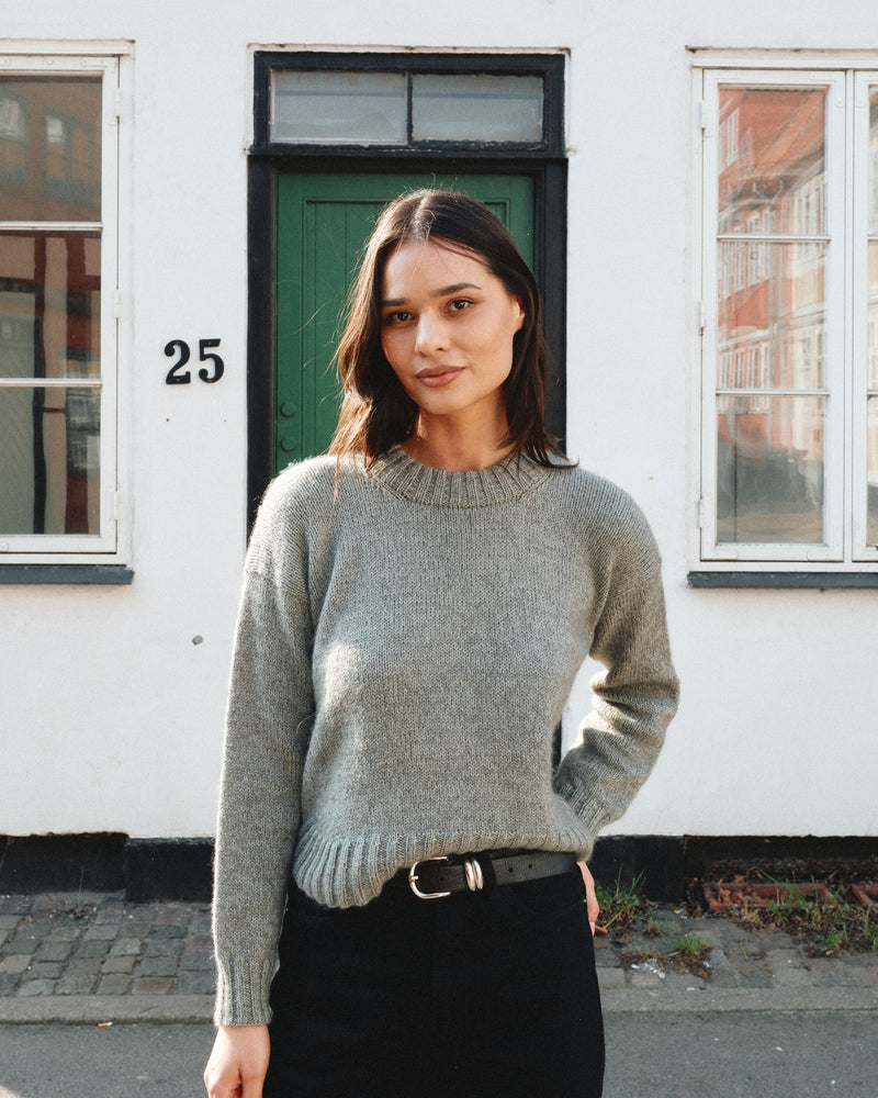 A woman wearing the Knitting for Olive Astrid Sweater, showing the relaxed fit and ribbed neckband