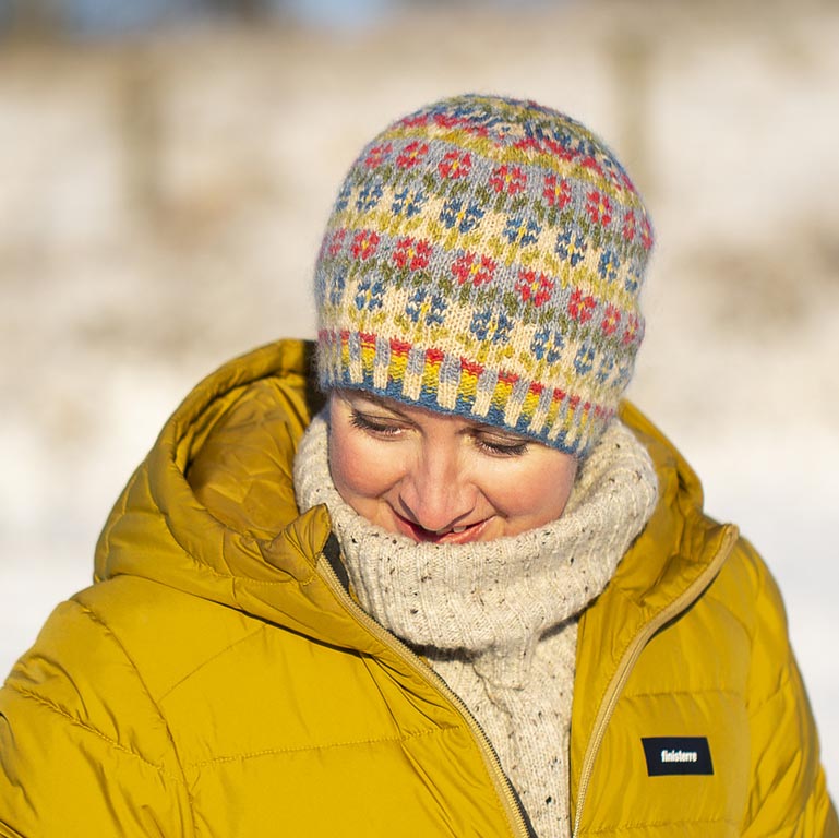Peerie Flooers hat worn, showing the rows of small flowers in seven Shetland shades