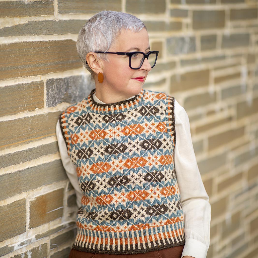 Starnkeeker vest worn over a white shirt, showing the allover star and cross motif in four Shetland shades