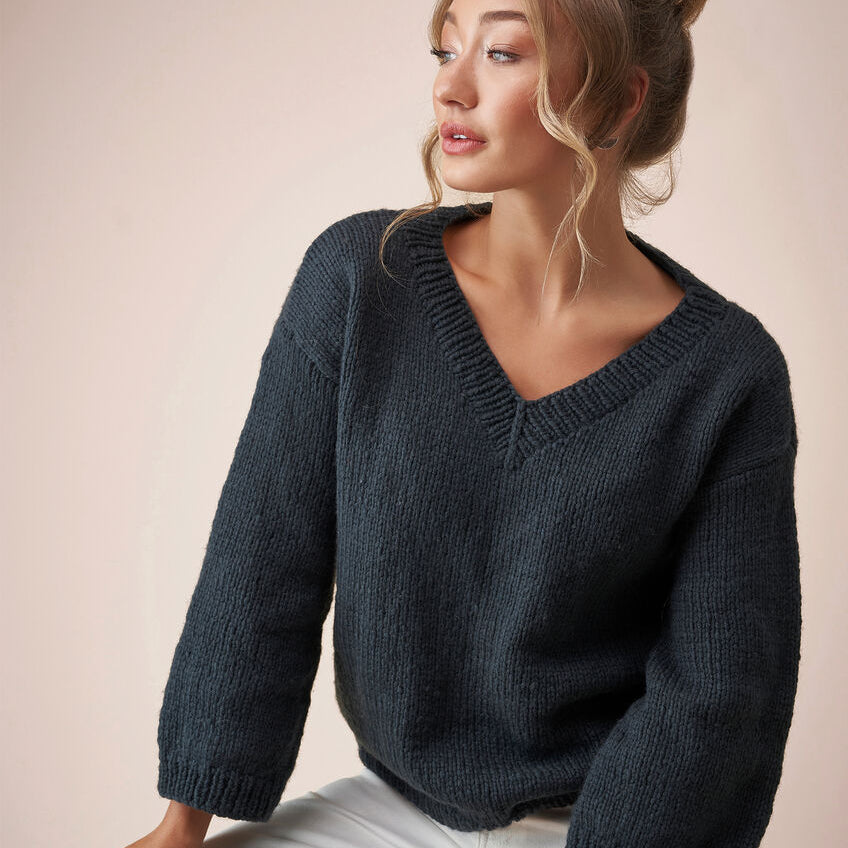 Woman wearing a dark blue knitted sweater against a beige background