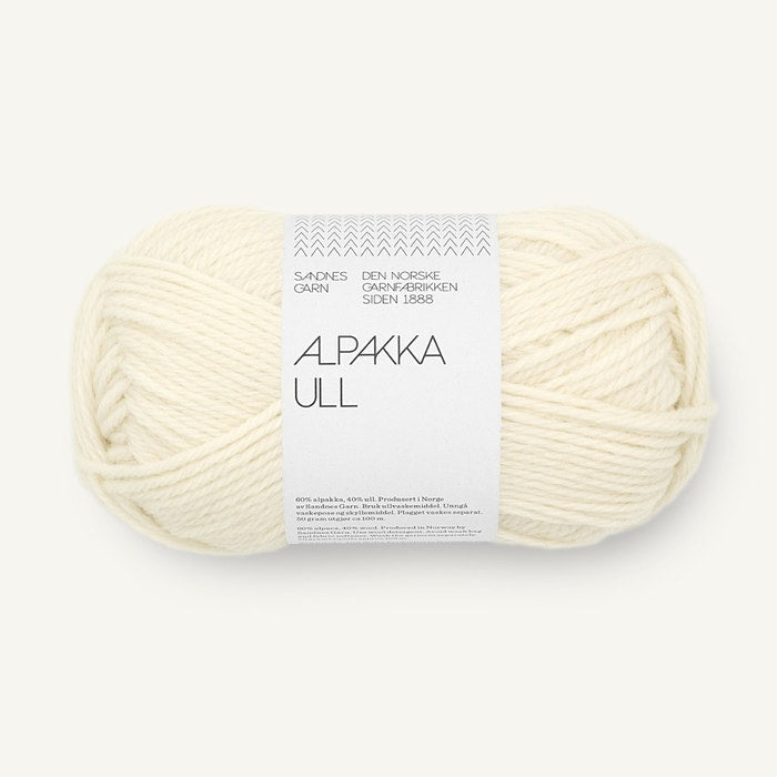 A skein of Alpaca Ull yarn in a warm cream color, wrapped with a white paper label that reads 'ALPAKA ULL' and 'SANDNES GARN', on a light off-white background.