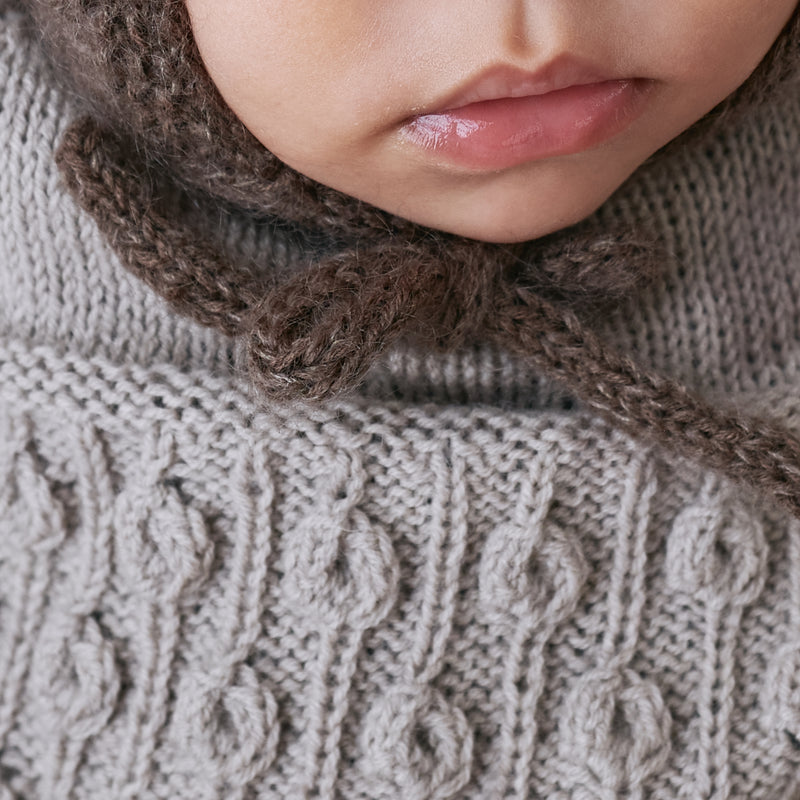Close-up of the I-cord tie and neck edge of the Knitting for Olive Baby Bear Bonnet worn by a baby