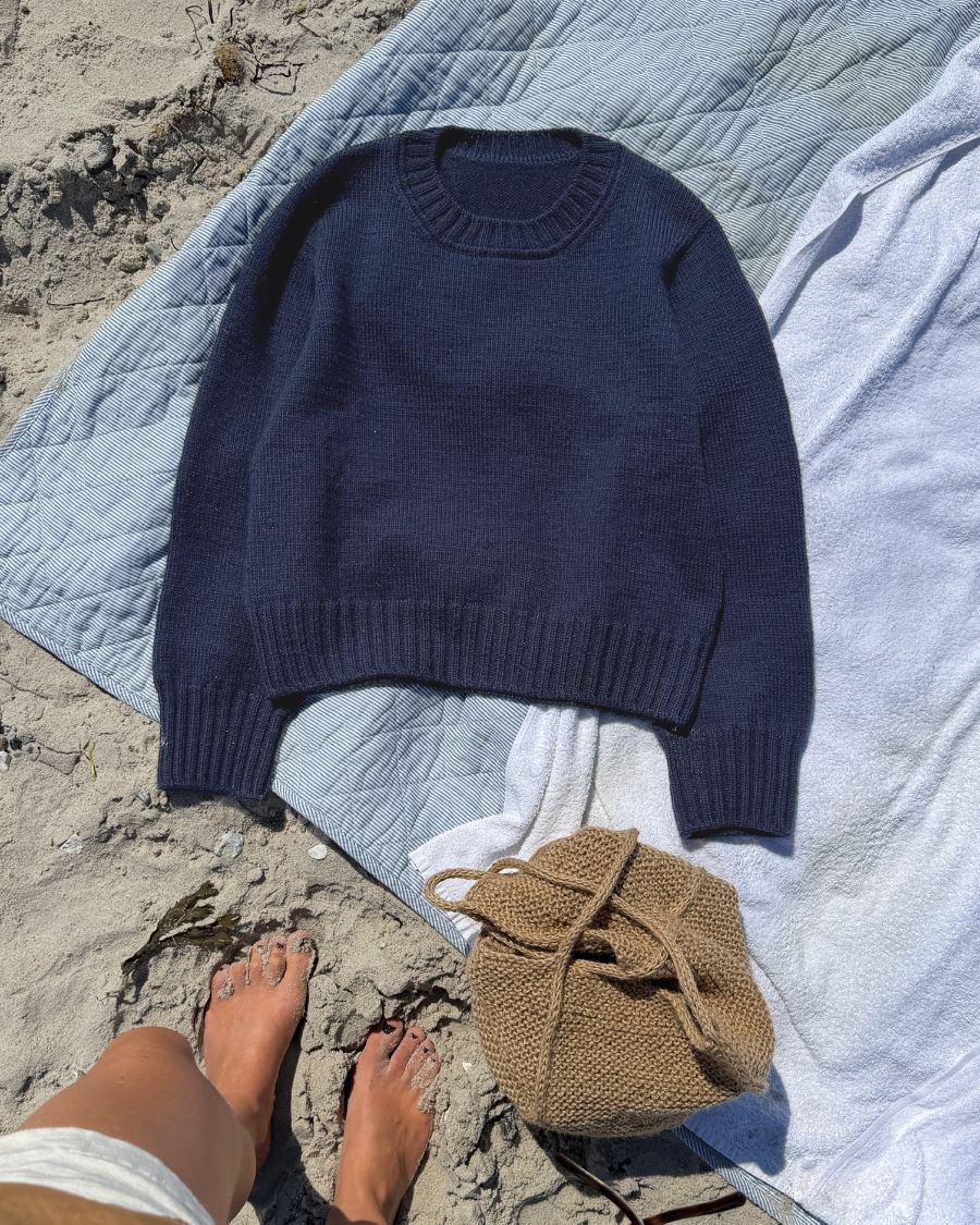 Blue PetiteKnit Vega Sweater laid flat on a beach blanket